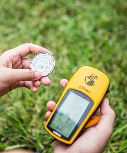 Image of a child holding a 4-H logo on a coin and a Garmin GPS navigator 